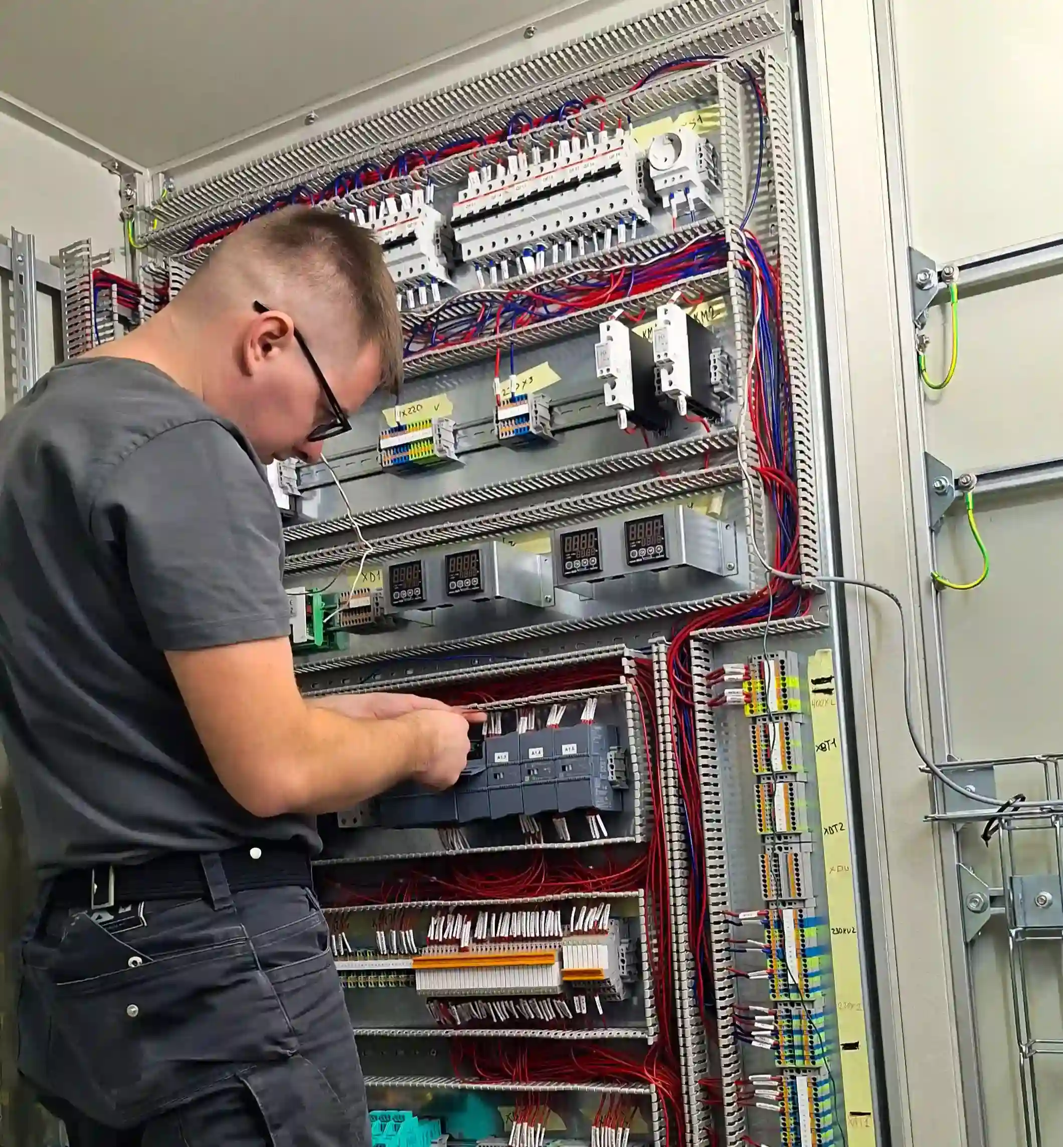 Elektrikár pri zapájaní rozvádzača počas elektroinštalačných prác - detailná práca s vodičmi a ističmi v rozvodnej skrini.