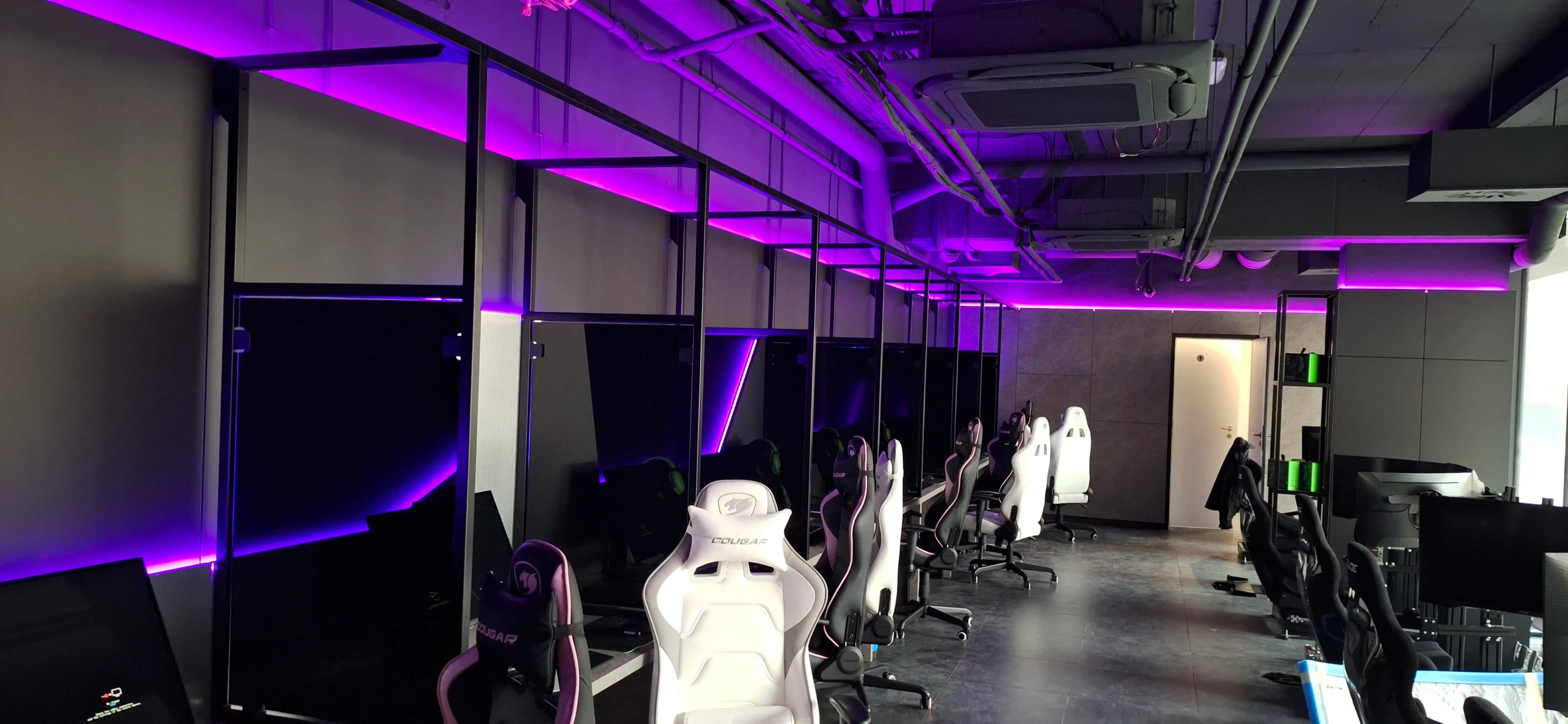 Celkový pohľad na interiér herne s radom výkonných počítačov a ambientným osvetlením.